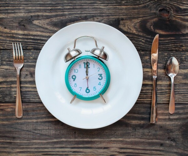 alarm clock, plate and fork and knife illustrating intermittent fasting