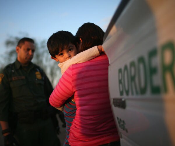 a border patrol agent watches a mother hug her child