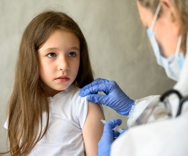 young girl looking fearful as she gets vaccine