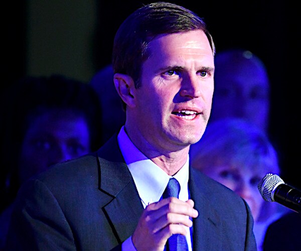 andy beshear speaks during a campaign rally with his family in the background