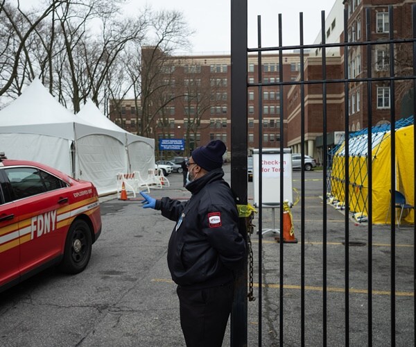 a guard at a gate oversees mobile coronavirus test structures