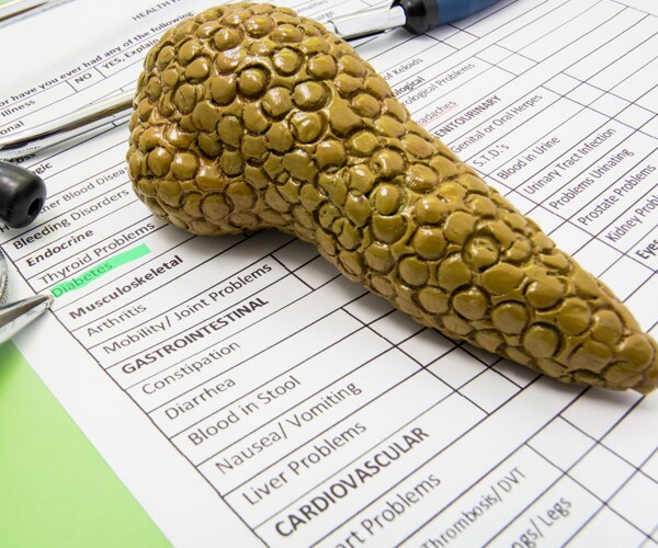 a model of a pancreas on top of a paper with the word diabetes highlighted in green