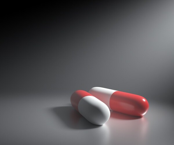 two capsules with blank background, signifying a covid antiviral in a pill