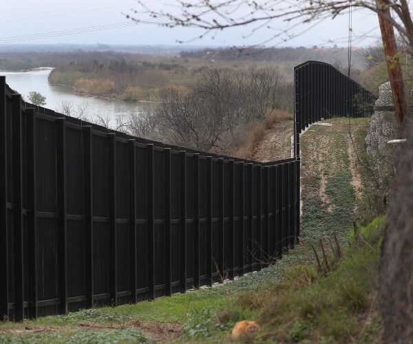 black border fence seen near the rio grande with trees on either side