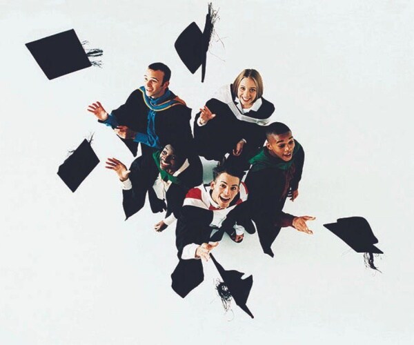 graduates in graduation gowns throwing their caps