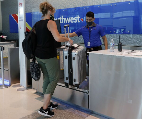 an airline employee assists a passenger, both wearing masks