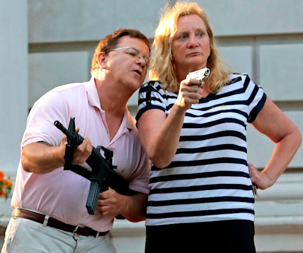 Mark and Patricia McCloskey hold their guns as protesters demonstrate outside their st. louis home