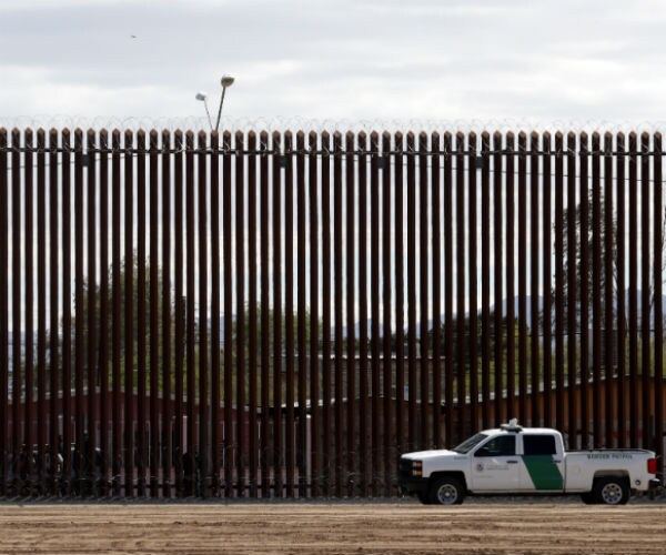 a white border patrol pickup truck is shown in front of a border wall in mexico