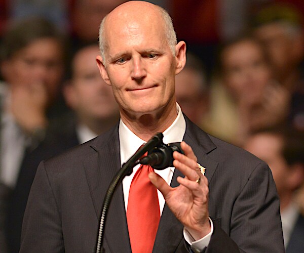 gop governor rick scott adjusts the mic in front of a campaign rally