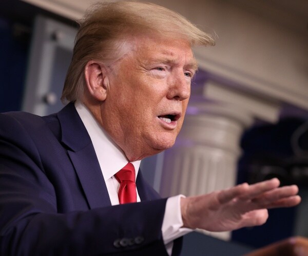 trump in a suit and red tie speaking in the press briefing room