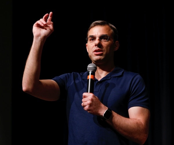 justin amash in a navy blue polo shirt speaking into a mic