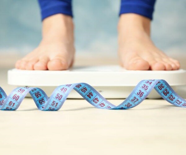 person's feet on scale with measuring tape around them