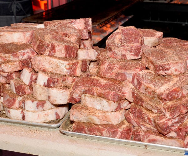 a huge pan of seasoned steaks are displayed