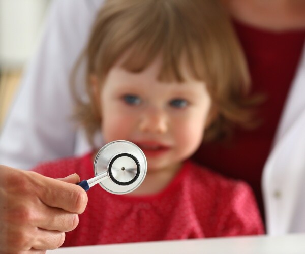 young child looks scared as a stethoscope comes near him