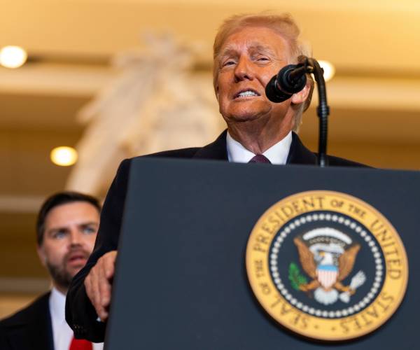 trump speaking into a microphone with jay dee vance standing behind him