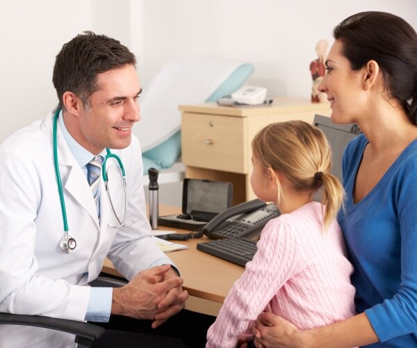 Doctor speaking to a mom and young child in office