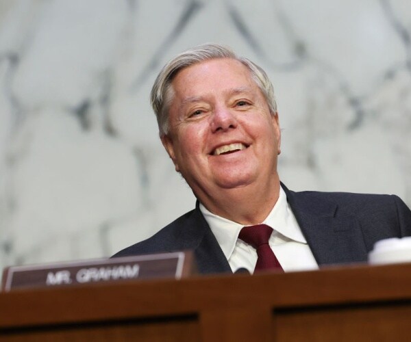 lindsey graham smiles with nameplate in front