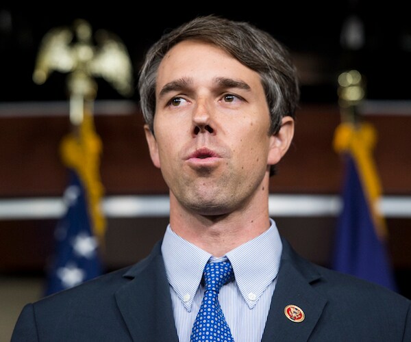 texas democrat beto o'rourke delivers remarks in front of a pair of american flags topped by eagles