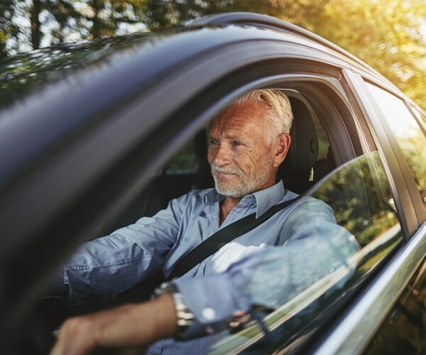 older man driving car with open window