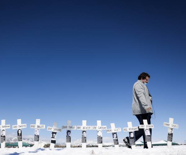 a person walking past crosses in the ground with names on them