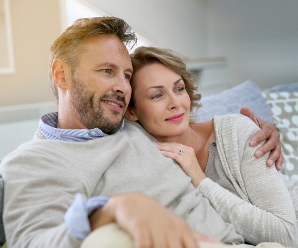 married couple smiling, sitting together on couch