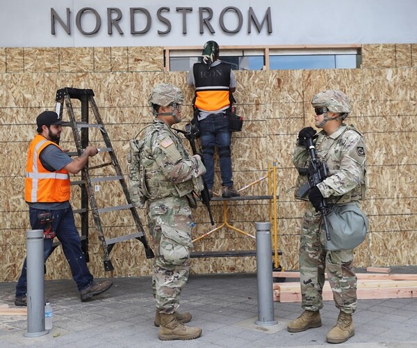 national guard stand outside a nordstrom that is boarding up