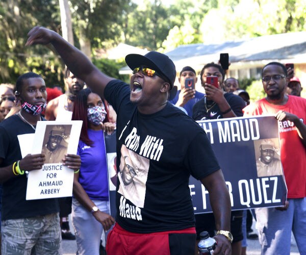 a man speaks to a crowd in a georgia neighborhood