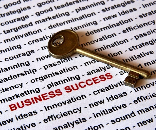 gold key with business success in red capital letters and other business terms in black on white in rear