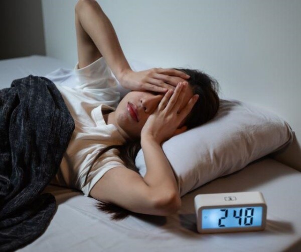 women suffering from insomnia in bed and clock shows it is 2 a.m.