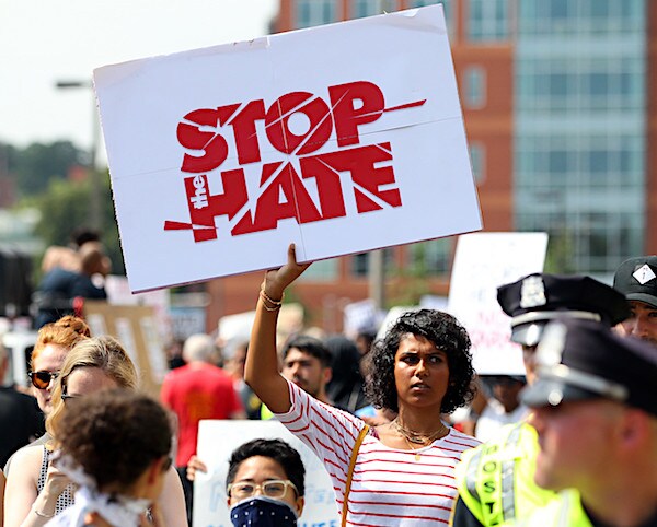 a protester holds up a stop the hate placard