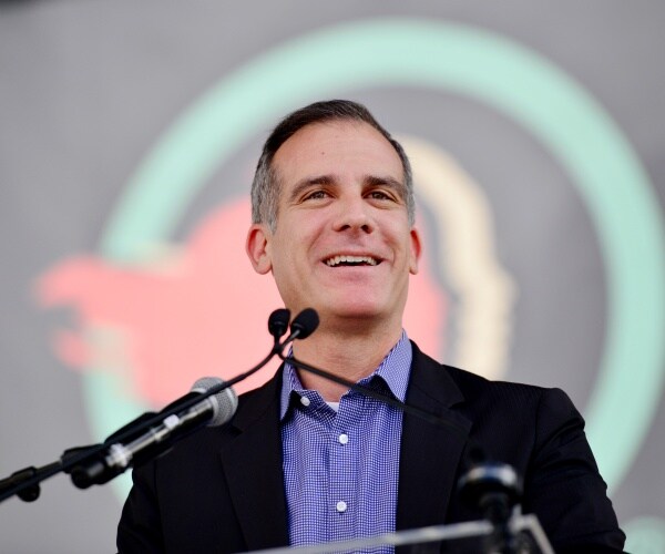 garcetti speaking at a podium in a blue dress shirt