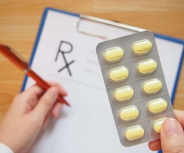 pharmacist holding a pack of pills while filling a prescription