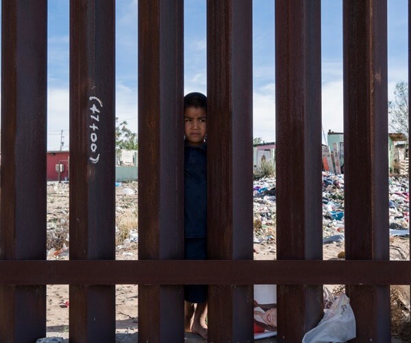 a little boy peers through border fence between u.s. and mexico