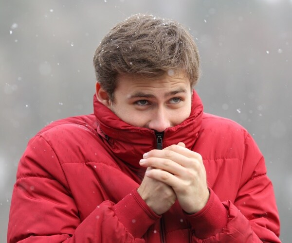 man outside in cold, snow without hat and shivering 