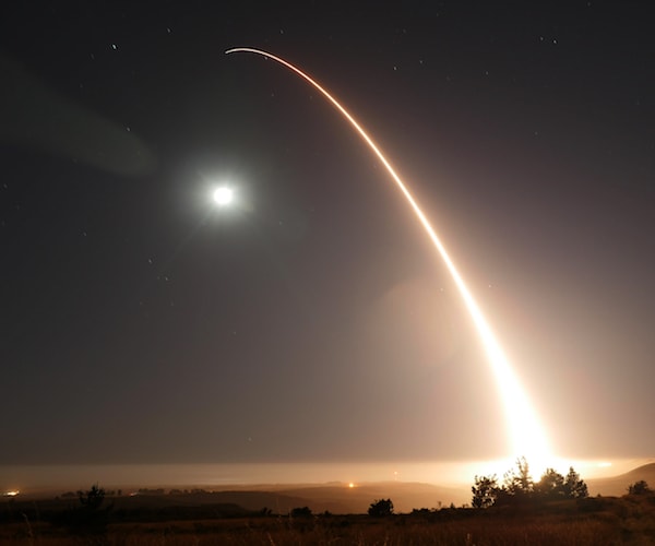 a united states intercontinental ballistic missile is launched into the night sky with a shining moon