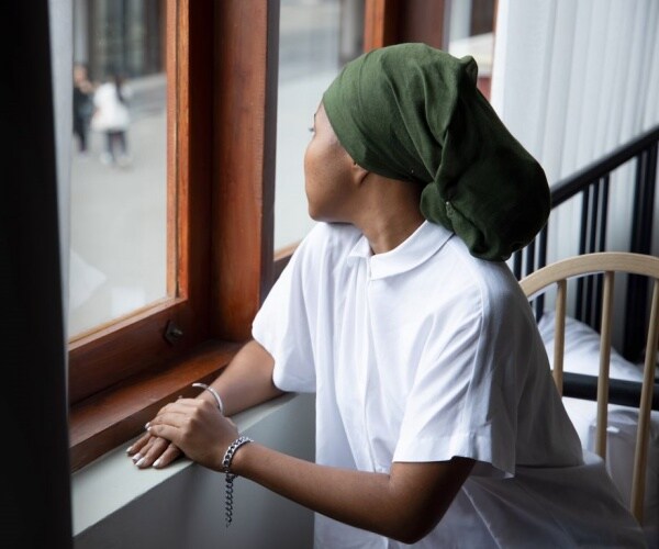 woman with scarf on head looking out window