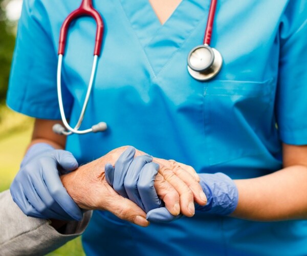 nursing home staff holding hand of an elderly patient