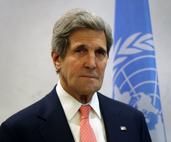 John Kerry  in front of a UN flag