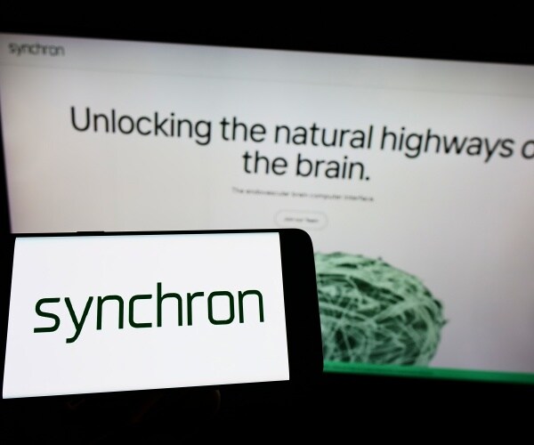 Synchron logo on smartphone in front of Synchron web page