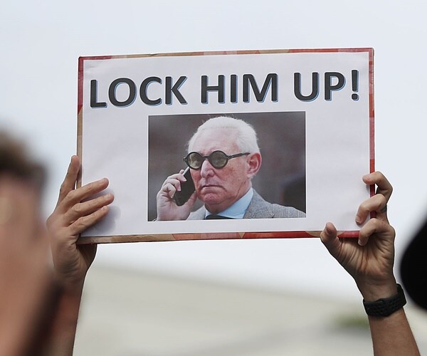 protesters hold up signs to lock up roger stone