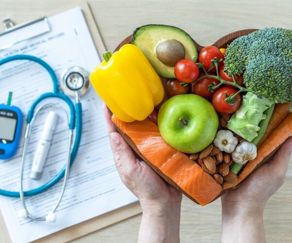 clipboard with stethoscope, glucose monitor and a heart-shaped plate with plant-based diet