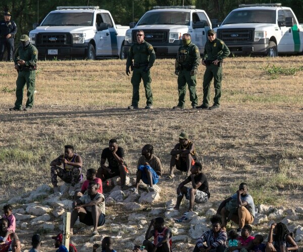 Border Patrol agents watch over immigrants near a migrant camp