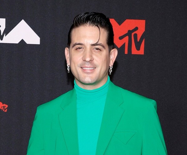 g eazy stands on red carpet in green suit