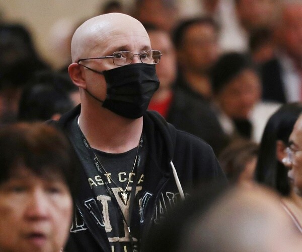 a man in a black mask for virus protection is in a church