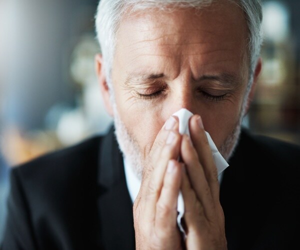 man in suit blowing nose