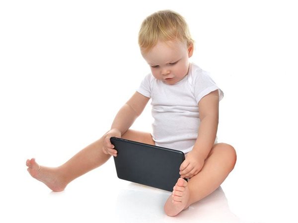 toddler sitting on ground looking at iPad