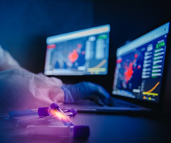 a medical professional in ppe clicks reload on the johns hopkins coronavirus data website