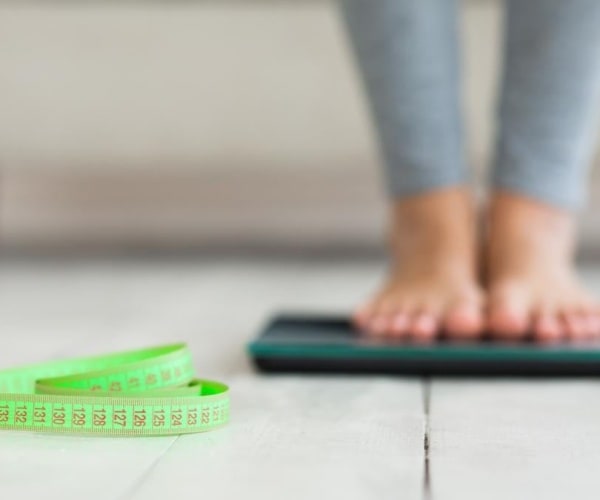 woman's legs on scale, a measuring tape on floor