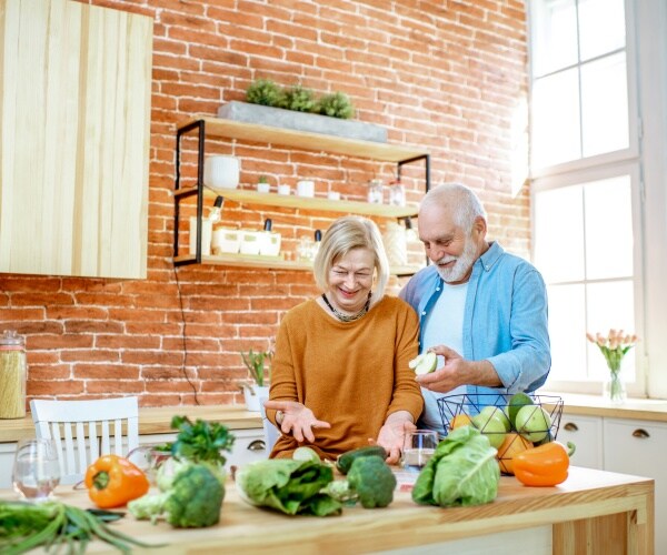 older man and woman preparing healthy foods in kitchen