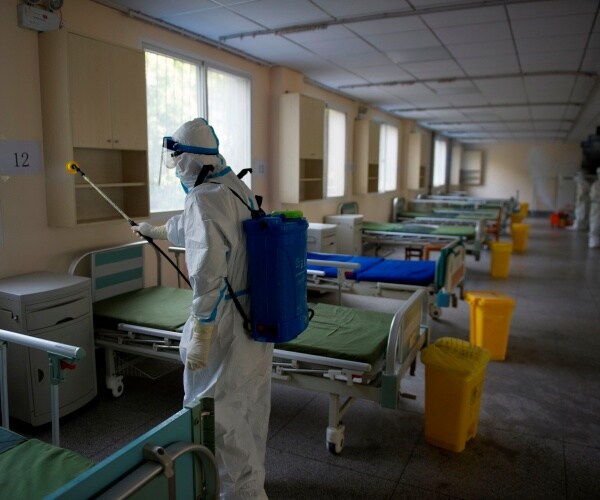 worker in protective suit disinfects an empty hospital room in Wuhan used to treat coronavirus patients